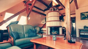 A cozy living room with a fireplace, wooden beams, a leather sofa, and a table with a candle.