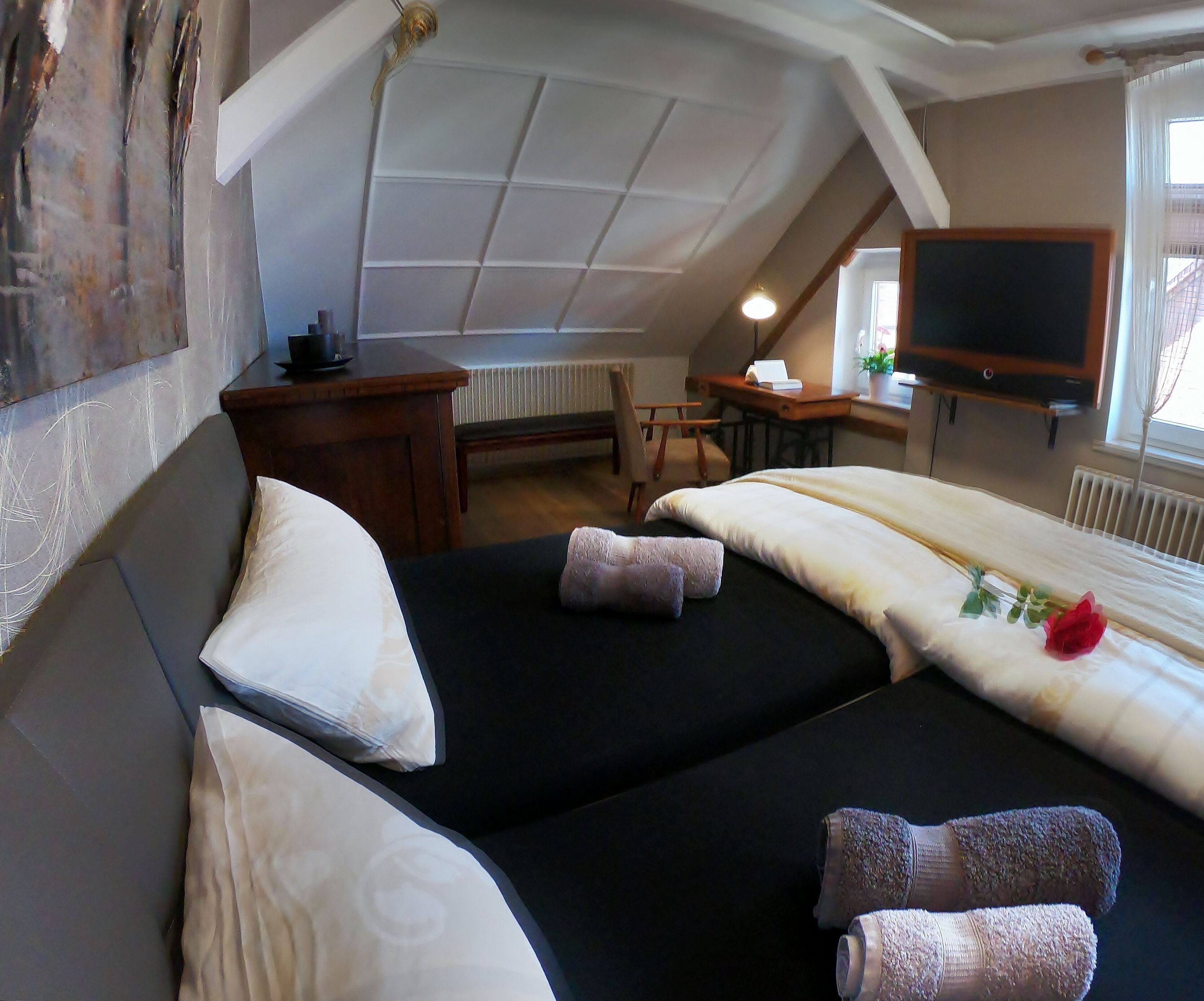 A bedroom with two beds, a desk, a chair, and a television.