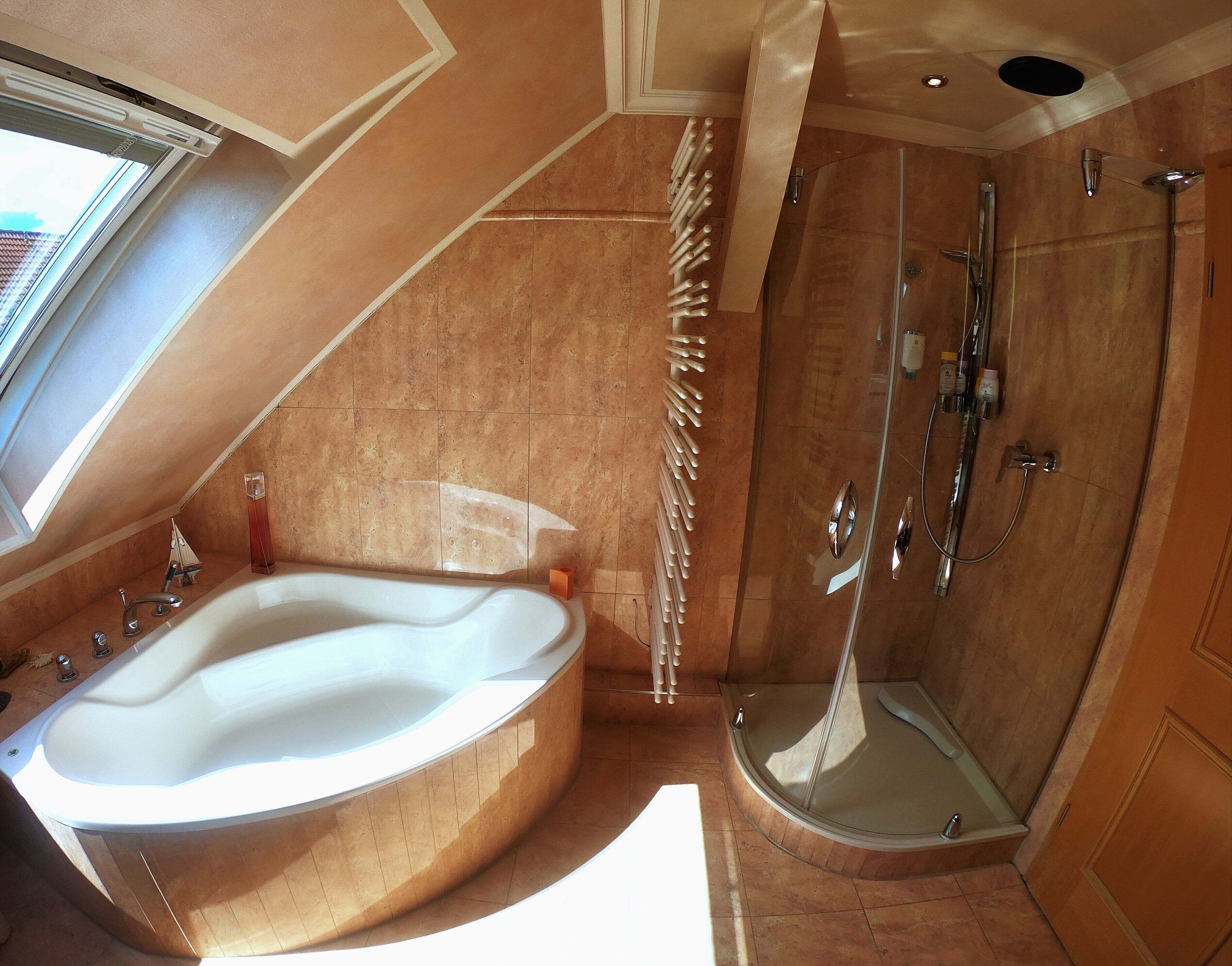 A bathroom with a large bathtub, a shower, and a skylight.