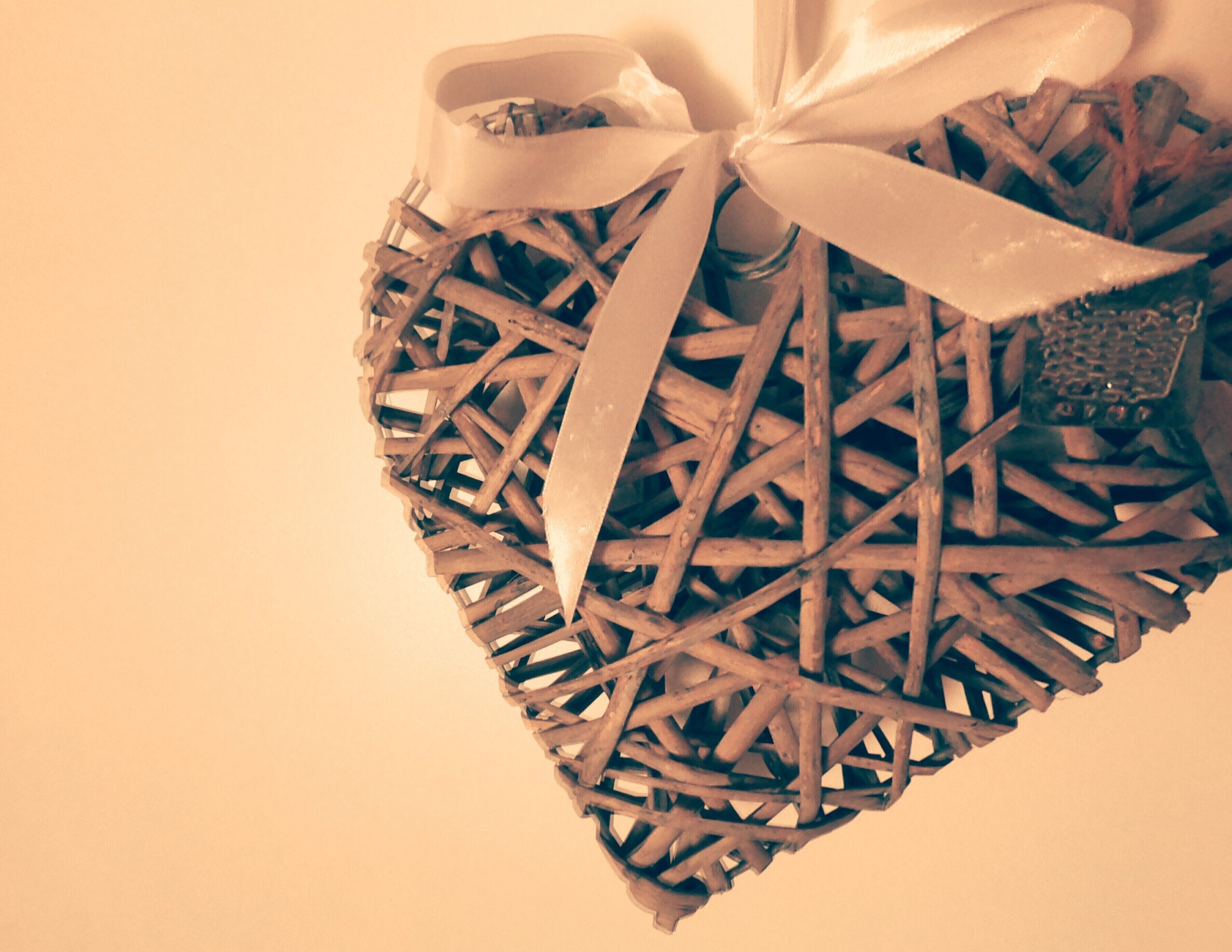 A heart-shaped wicker decoration with a ribbon and a small ornament.