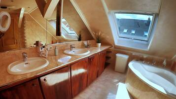 Un bagno moderno con due lavabi, uno specchio grande, armadietti in legno e un lucernario.