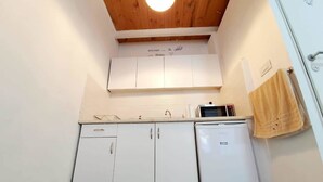 A compact kitchen with white cabinets, a microwave, and a refrigerator.
