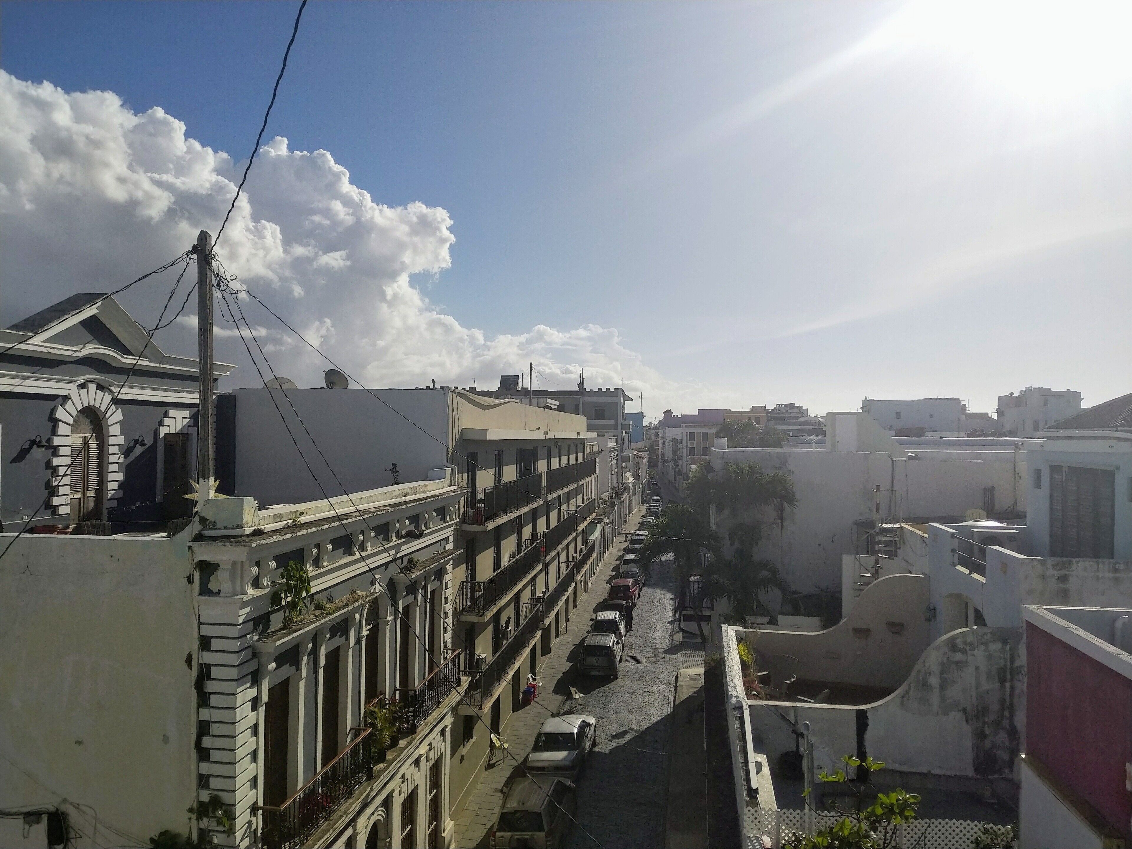 Un immeuble à plusieurs étages doté de balcons, une rue en contrebas et un ciel dégagé.