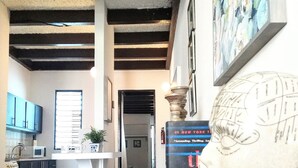 Eine Küche mit Holzstühlen, einer weißen Arbeitsplatte und einer Mikrowelle. An der Wand hängt ein gerahmtes Kunstwerk und auf dem Tisch steht ein Globus.