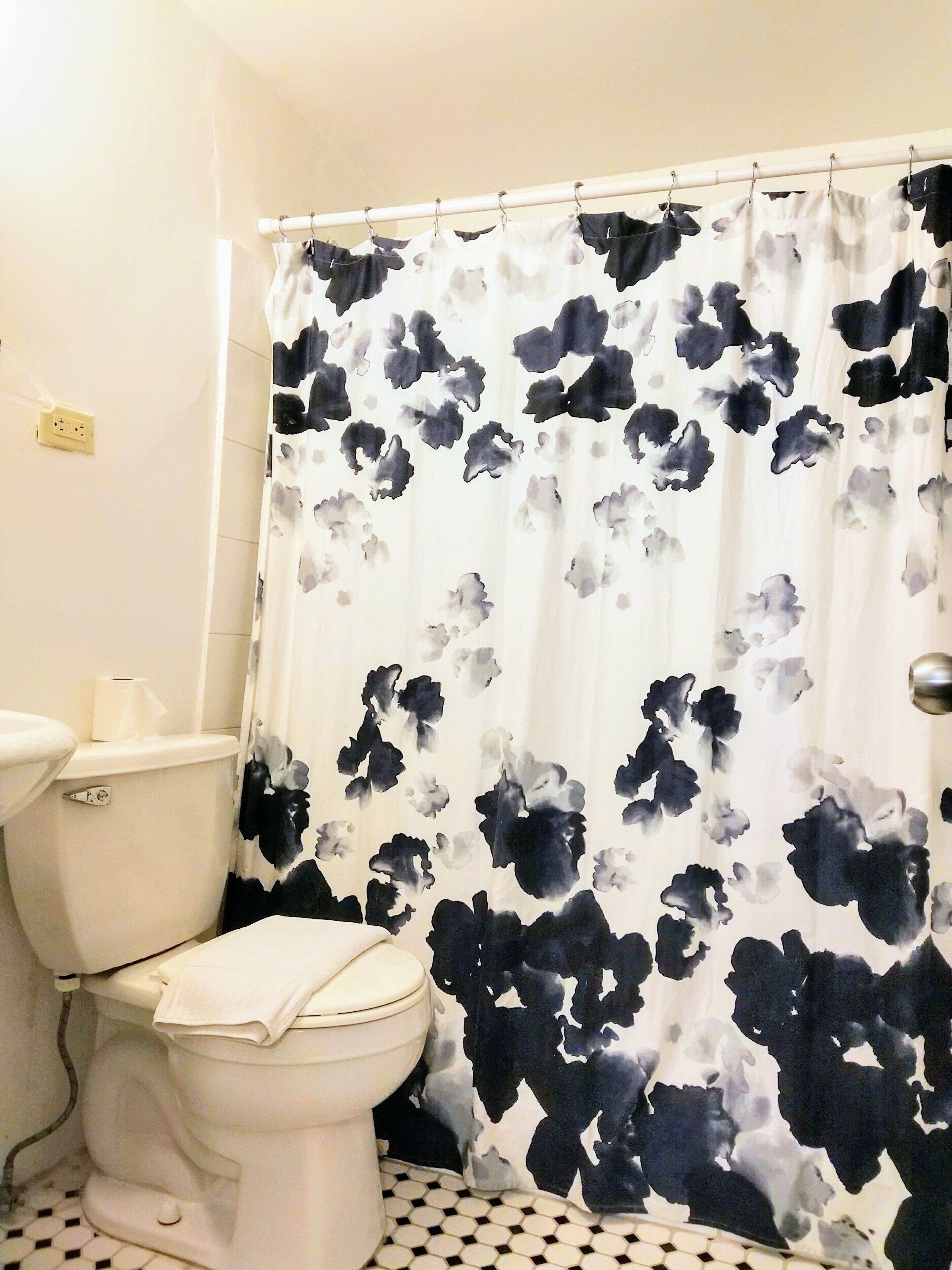 A bathroom with a toilet, a sink, and a shower curtain with a floral pattern.