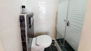 A small bathroom with a toilet, a shower, and a sink. - Agas Holiday Apartments Gefen Boutique (Tiberias)