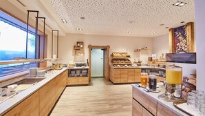 A modern kitchen with wooden cabinets, a breakfast bar, and a large window. - Rosentalerhof Hotel & Apartments (Saalbach-Hinterglemm)