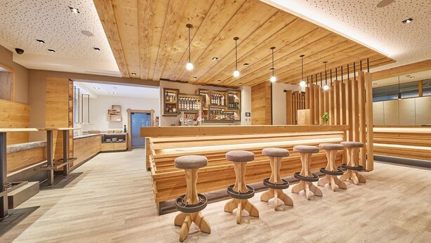 A modern bar area with wooden stools, a bar counter, and a wooden ceiling. - Rosentalerhof Hotel & Apartments (Saalbach-Hinterglemm)
