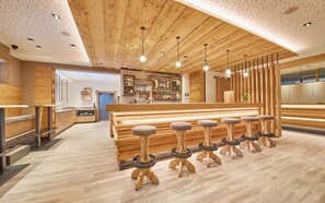 A modern bar area with wooden stools, a bar counter, and a wooden ceiling. - Rosentalerhof Hotel & Apartments (Saalbach-Hinterglemm)