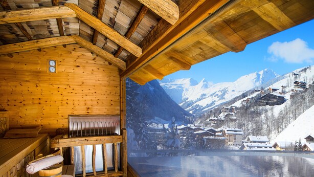 A wooden cabin with a sauna, wooden benches, and a view of a snowy mountain landscape. - Wellnesshotel Alpin Juwel (Saalbach-Hinterglemm)