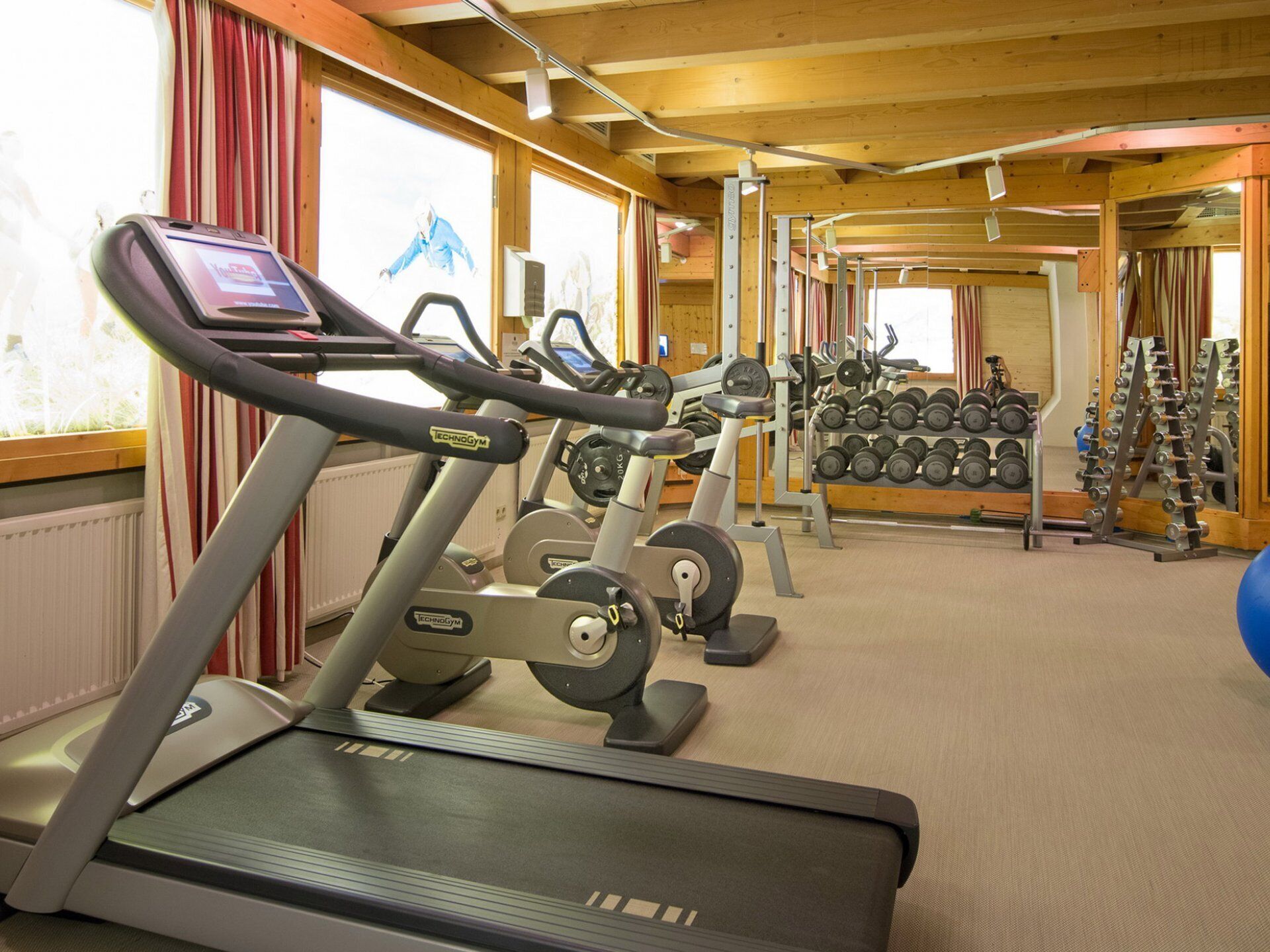 A gym with treadmills, weight machines, and dumbbells.