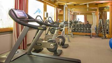 A gym with treadmills, weight machines, and dumbbells.