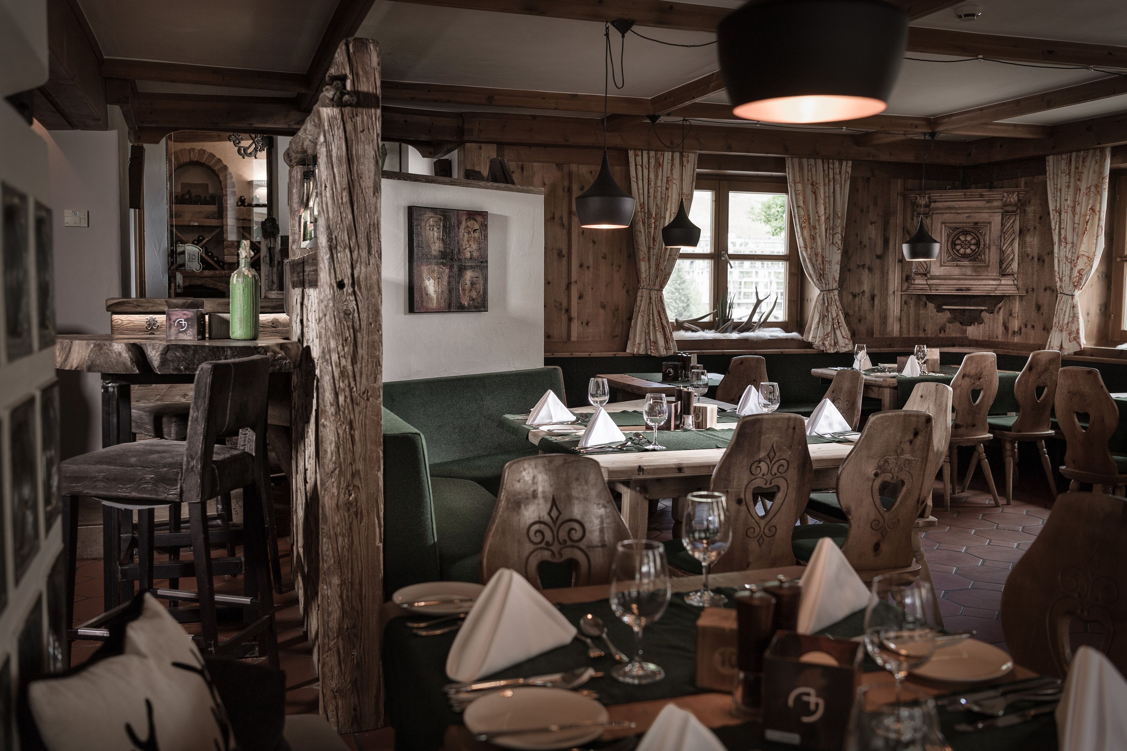 Un coin repas rustique, avec des meubles en bois et un banc recouvert d’un tissu vert.