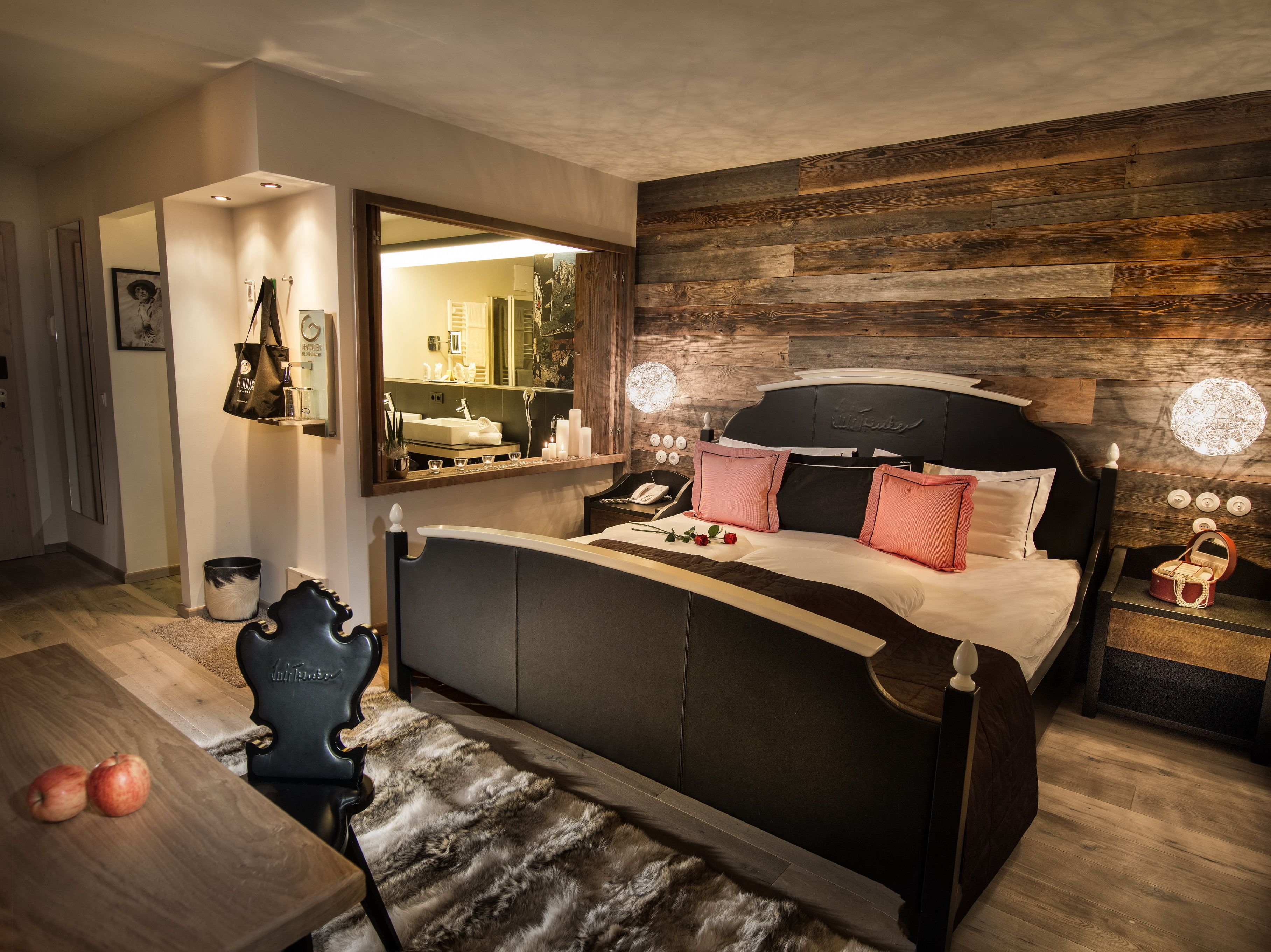 Un dormitorio moderno con una cama grande, un tocador con espejo y una pared de madera decorativa.