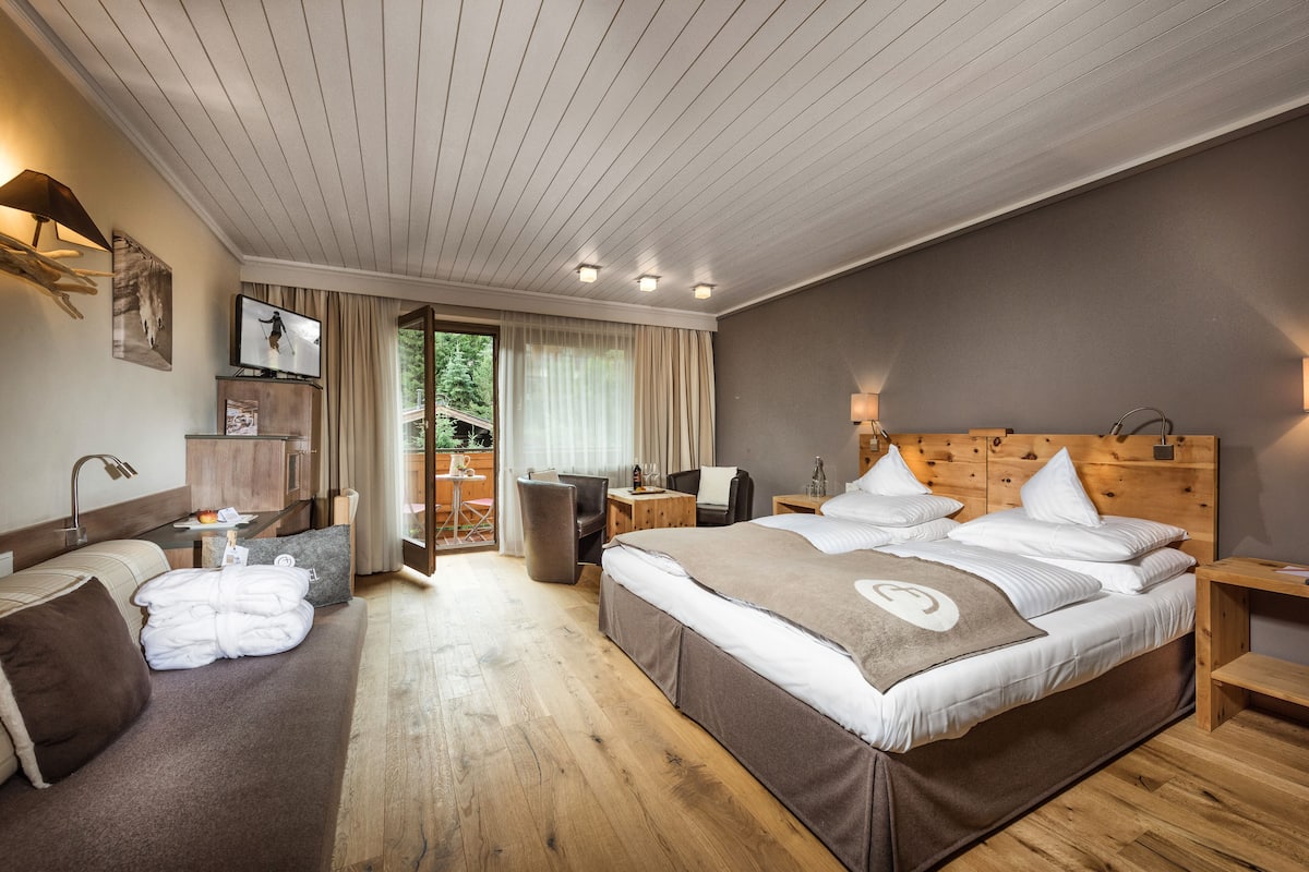Une chambre d’hôtel avec un grand lit, un canapé, un bureau et une télévision.