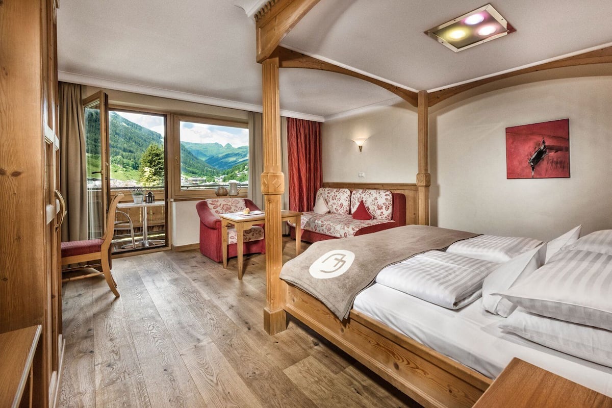 Une chambre à coucher en bois, avec un lit, une table et une chaise. Il y a une fenêtre qui donne sur les montagnes.