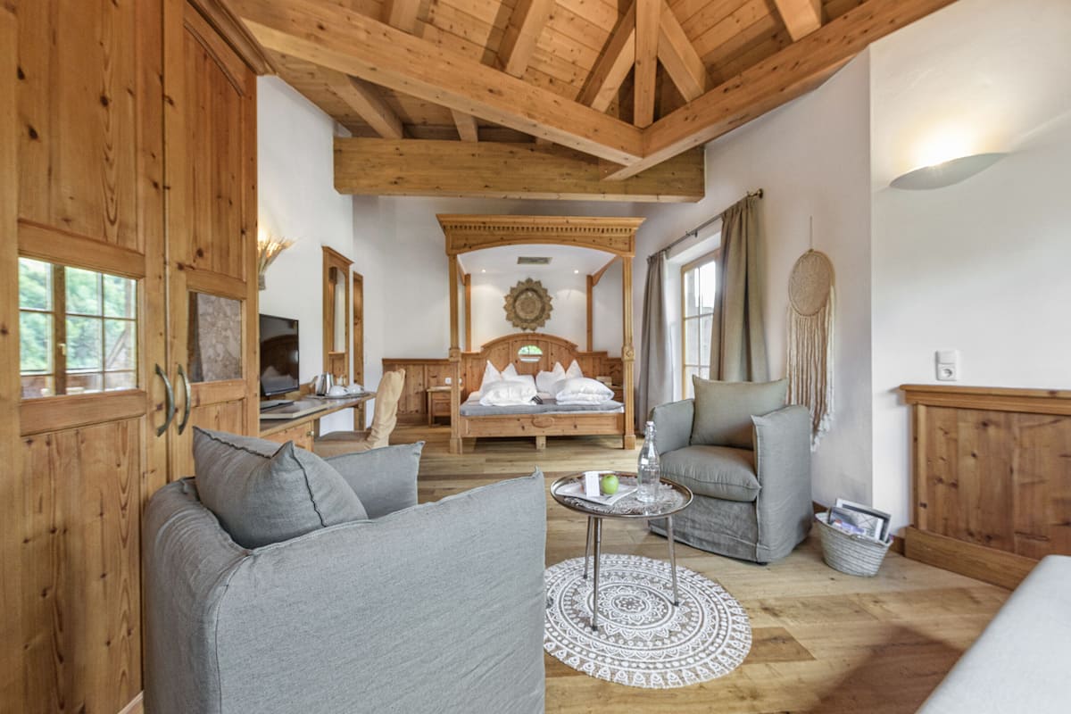 Une pièce chaleureuse avec un lit, deux canapés, une table basse et des poutres en bois au plafond.