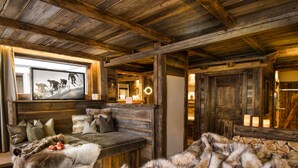 A rustic cabin interior with a wooden bench, fur throw, and candles. - Wellnesshotel Alpin Juwel (Saalbach-Hinterglemm)
