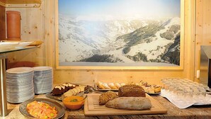 Un bufé de desayuno con diversas opciones de comida y una vista panorámica a las montañas.