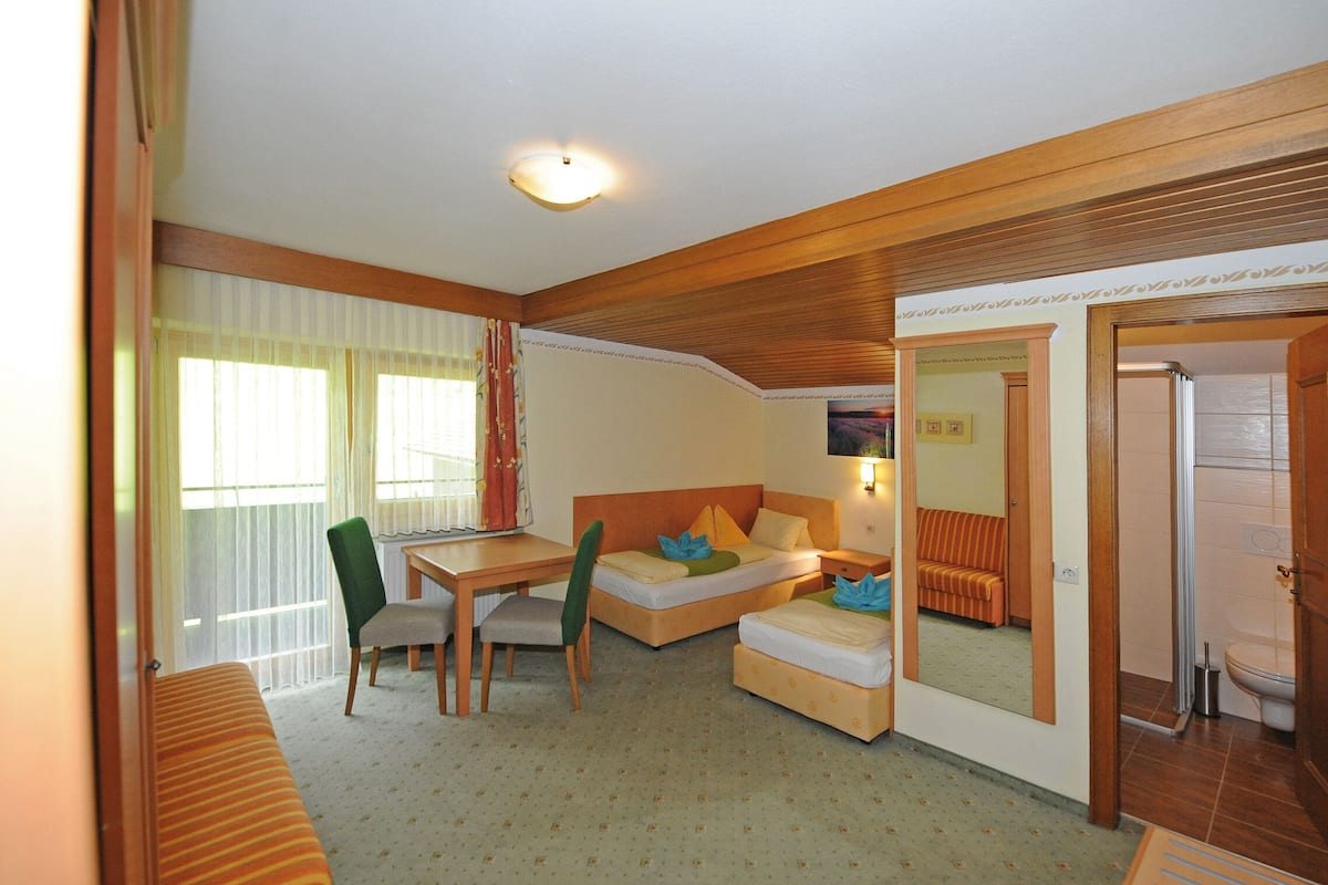 Habitación de hotel compacta con cama, escritorio, silla, sofá y baño.