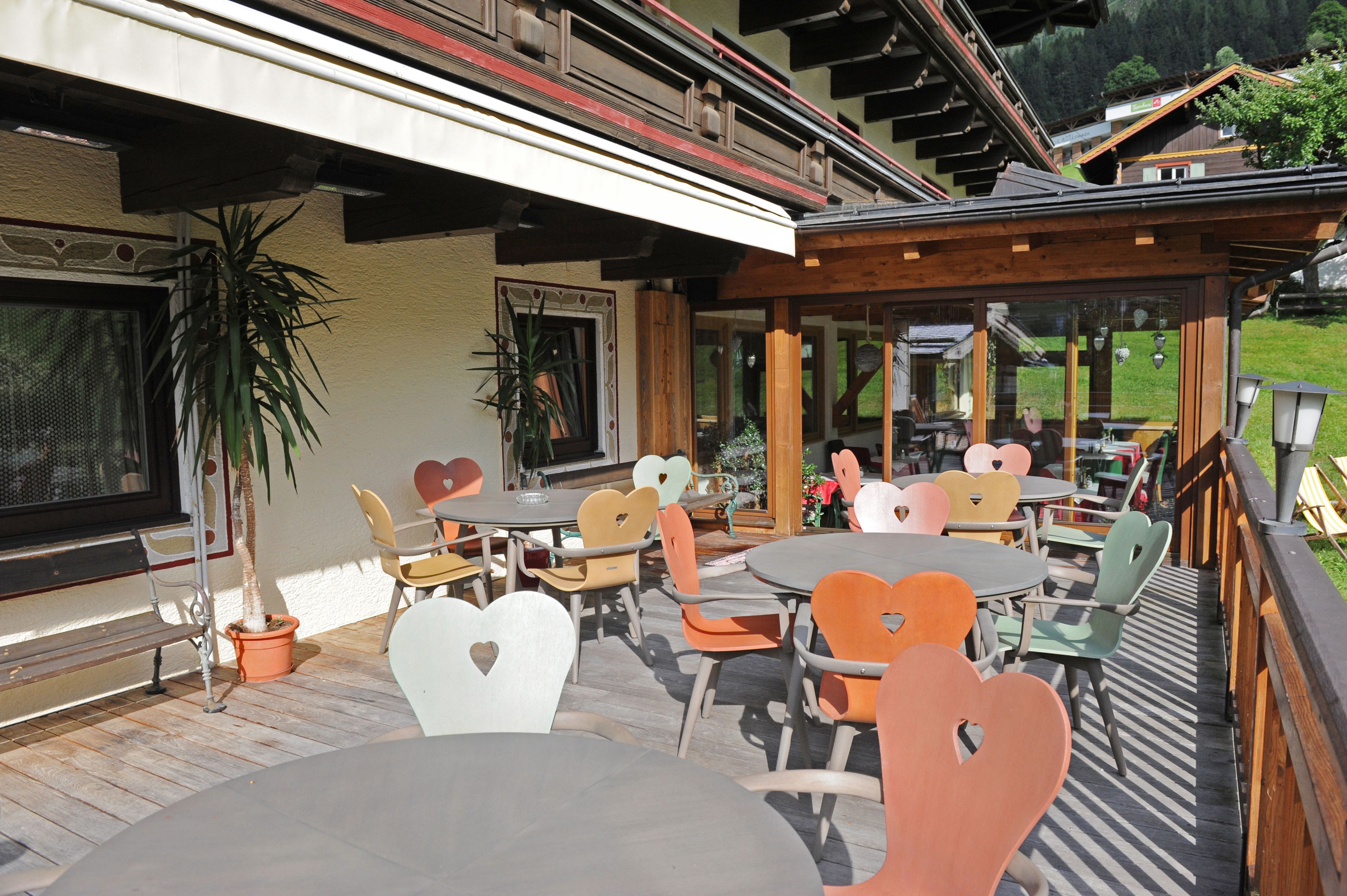 Eine Terrasse im Freien mit tisch- und stuhlförmigen Herzchen, umgeben von einem Holzboden und einer Glaskonstruktion.