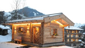 Una cabaña de madera con un banco de madera en el exterior, una puerta de madera y un letrero que dice "Unterellhaus".