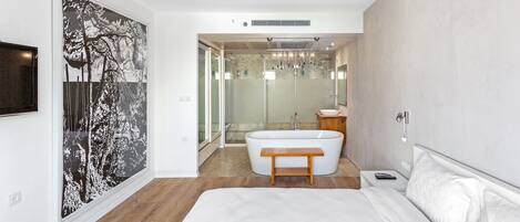 Un dormitorio moderno con una cama grande, una bañera y una ducha a ras de suelo.