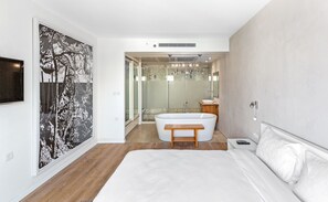 A modern bedroom with a large bed, a bathtub, and a walk-in shower. - Lagoon Amazing water front 3 (Herzliya)