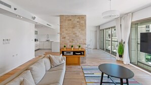 A modern living room with a sofa, a coffee table, and a stone accent wall. - Lagoon Amazing water front 3 (Herzliya)