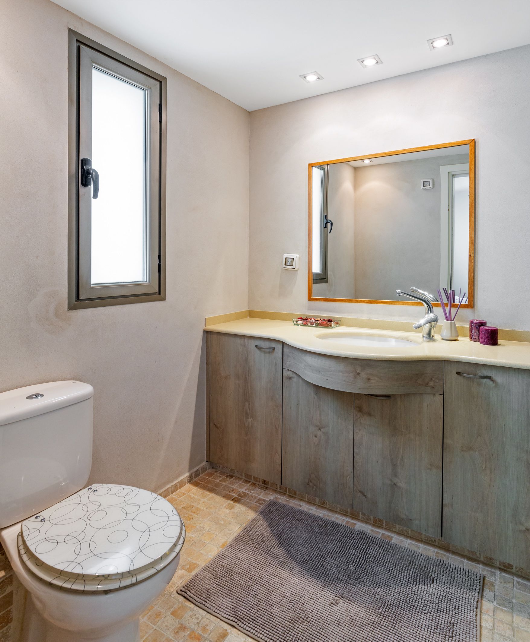 A bathroom with a toilet, a sink, and a mirror.