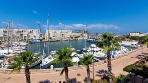 A marina with boats docked, palm trees, and buildings in the background. - Lagoon Amazing water front 3 (Herzliya)