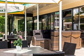 An outdoor seating area with wicker furniture and a covered patio. - Trend Hotel (Banzkow)