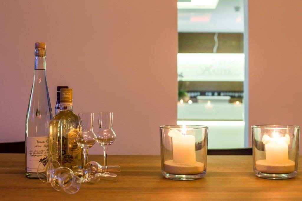 A table with a bottle of wine, wine glasses, and two lit candles.