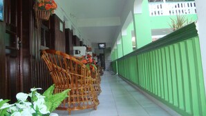 A corridor with wicker furniture and potted plants, leading to a green wall and a tiled floor. - Lubas Hotel (Rosario)