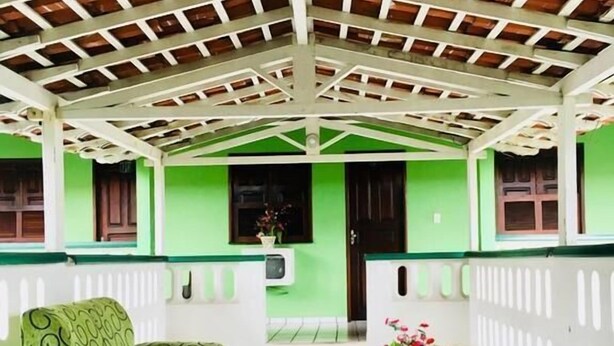 A covered outdoor area with a tiled floor, green walls, and a white railing. - Lubas Hotel (Rosario)