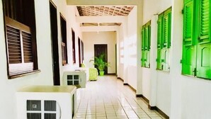 A corridor with tiled flooring, a ceiling with exposed beams, and green shutters on the windows. - Lubas Hotel (Rosario)