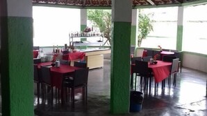 A restaurant with tables and chairs, a kitchen area, and a view of the outdoors. - Lubas Hotel (Rosario)