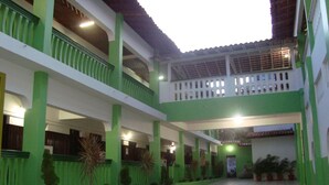 A courtyard with a tiled floor, green and white walls, and multiple balconies. - Lubas Hotel (Rosario)