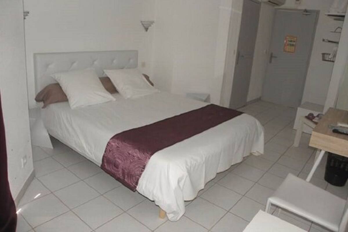 A hotel room with a bed, a desk, and a chair.