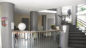 A reception area with a curved counter, metal railings, and a staircase leading to an upper level. - Hôtel la clé (Saint-Andre-de-Sangonis)