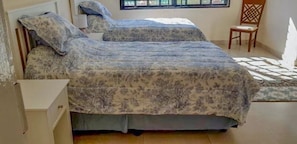 A bedroom with two beds, a chair, and a window.