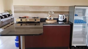 A compact kitchen with a built-in stove, a coffee maker, and a refrigerator. - Makeni Villa (Lusaka)