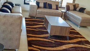 A modern living room with a sofa set, a coffee table, and a patterned rug. - Makeni Villa (Lusaka)