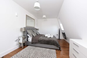 Un dormitorio moderno con cama, mesita de noche y espejo.