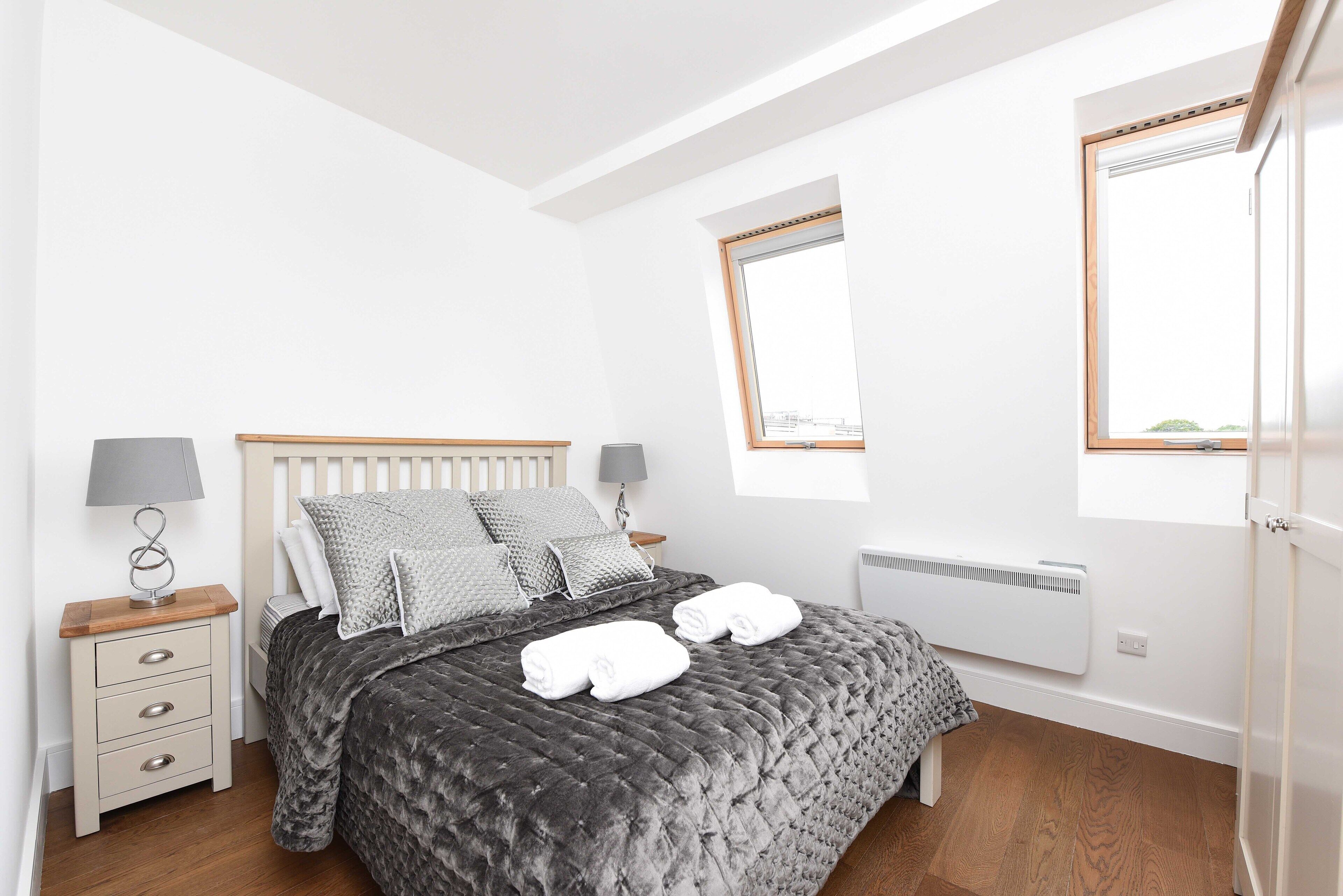 A bedroom with a bed, bedside tables, lamps, and a window.