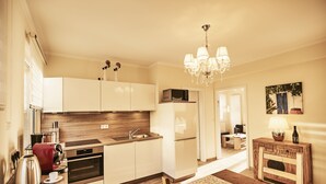 A modern kitchen with wooden cabinets, a built-in oven, and a dining area with a wooden table and chairs.