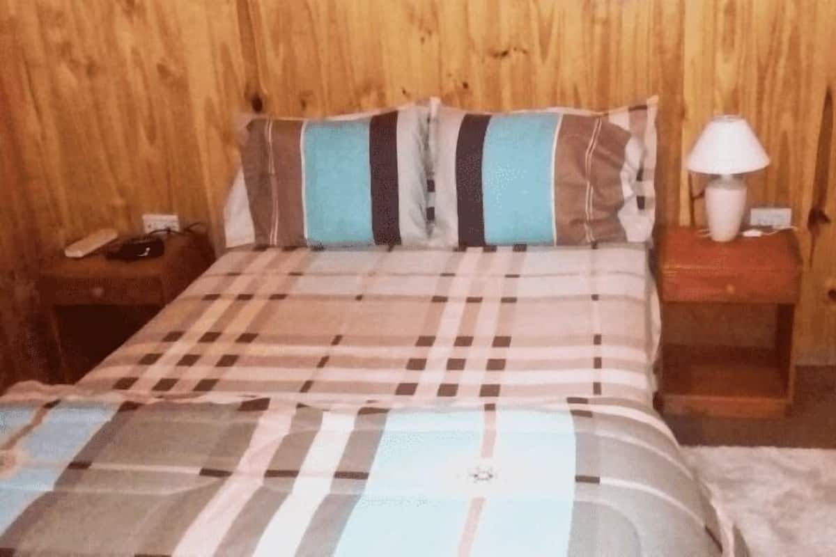 Une chambre avec un lit, une table de chevet, une lampe et un téléphone.