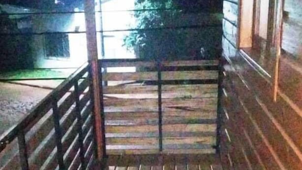 Una terraza de madera con barandilla metálica que conduce a la entrada de un edificio.