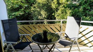 A balcony with a round table and two chairs, surrounded by a wooden railing. - Residenz Schauinsland (Todtnau)