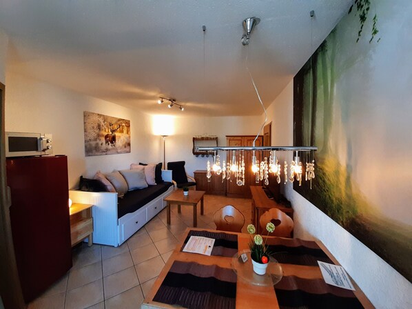 Una sala de estar moderna con sofá, mesa de comedor y un cuadro en la pared.